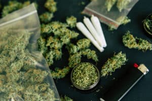 Macro of marijuana bud with trichomes and crushed weed for chopping a canabis on a black table